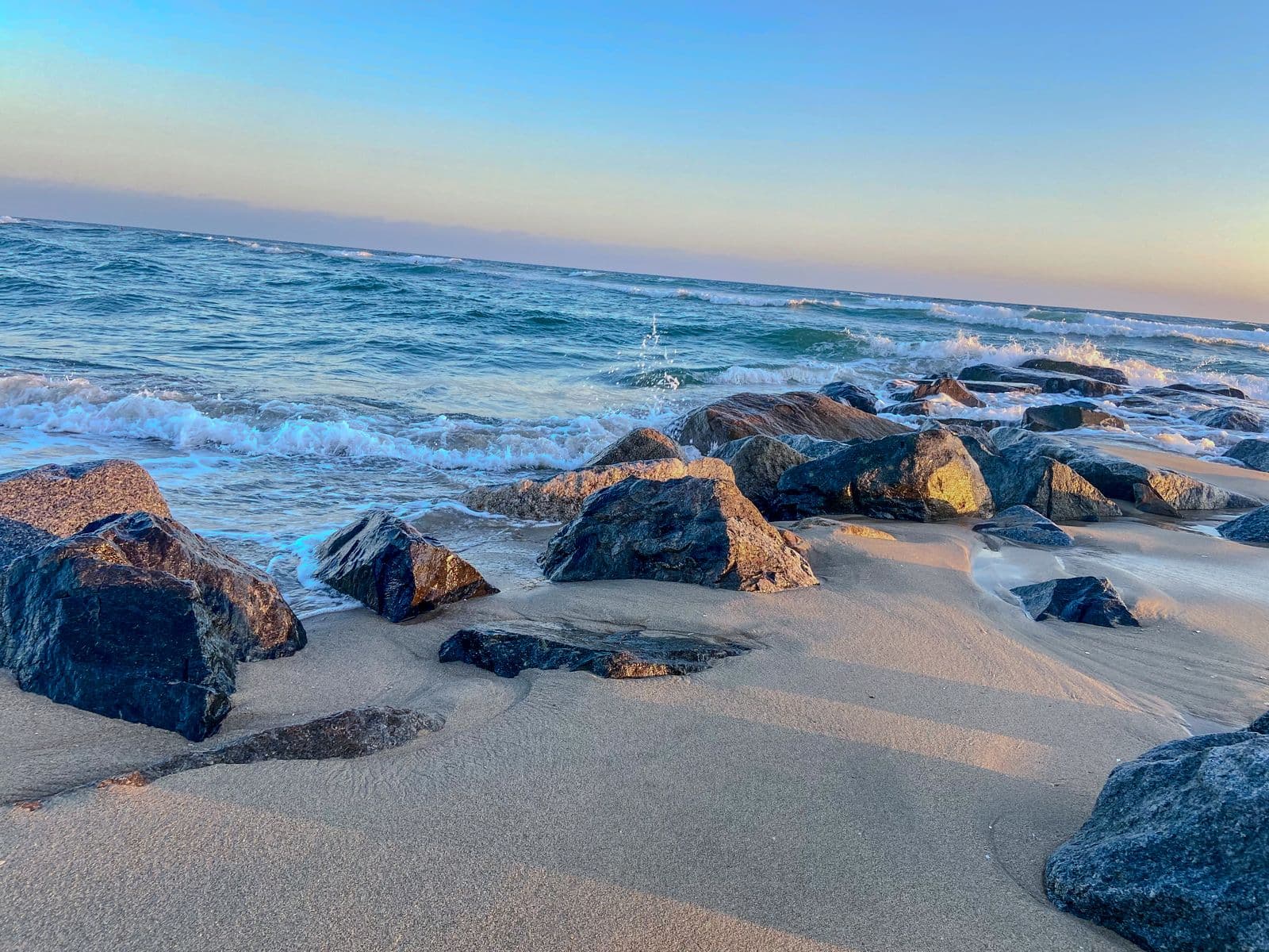 Low surf washing over dark rocks on a quiet beach